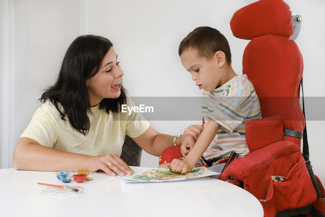 Child with cerebral palsy painting with fingers and hands boy that has health problems developing