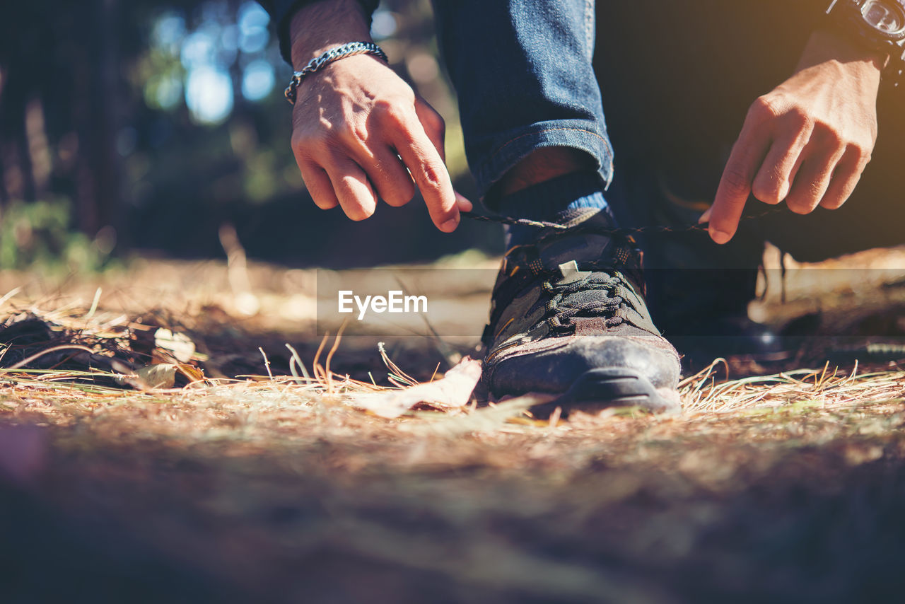 Low section of man tying shoe on field