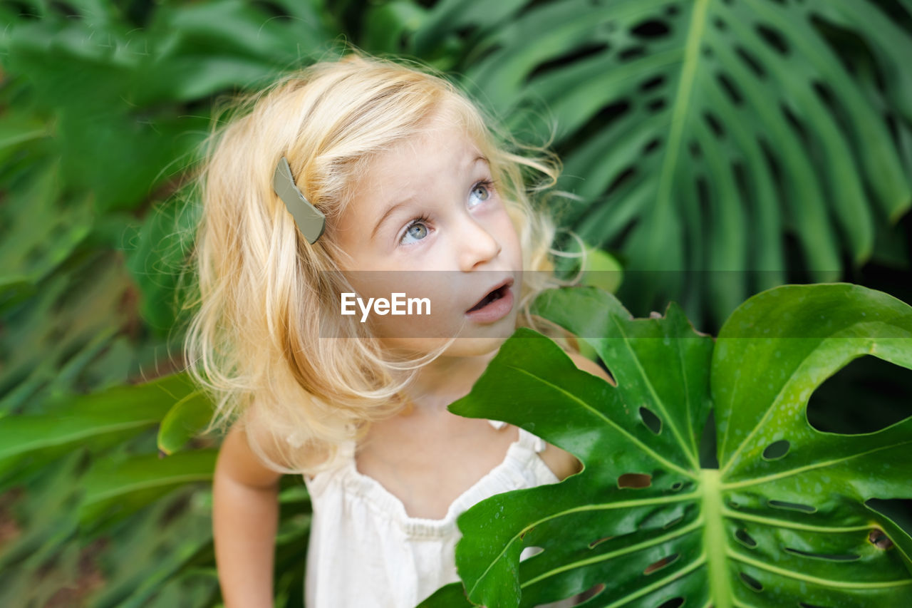 Portrait of little girl standing amidst green plants