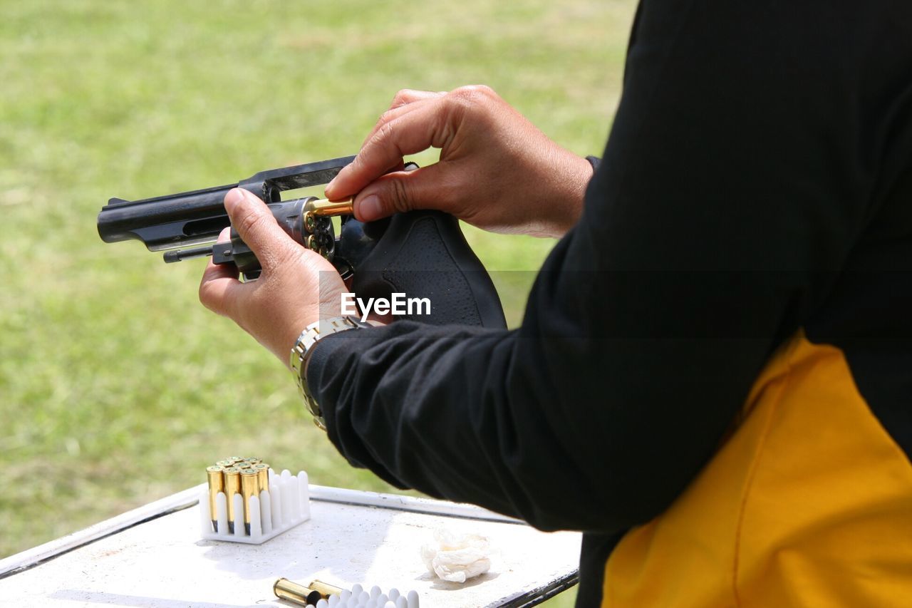 Cropped image of man loading bullets in gun
