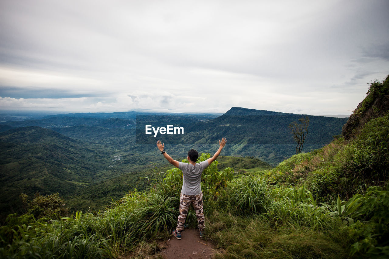 Rear view of man standing on mountain against sky