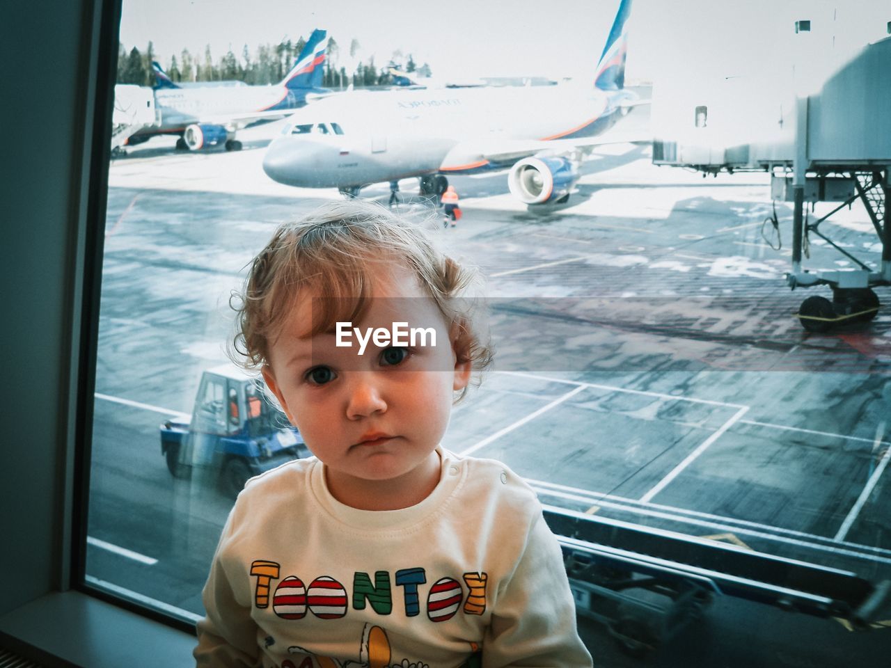 Portrait of cute girl at airport terminal against window