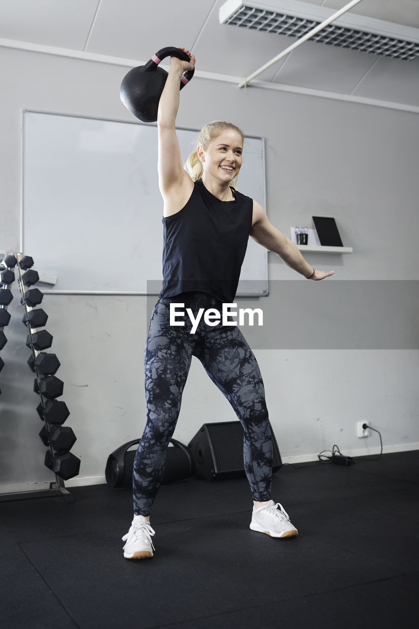 Blond woman lifting weights in gym