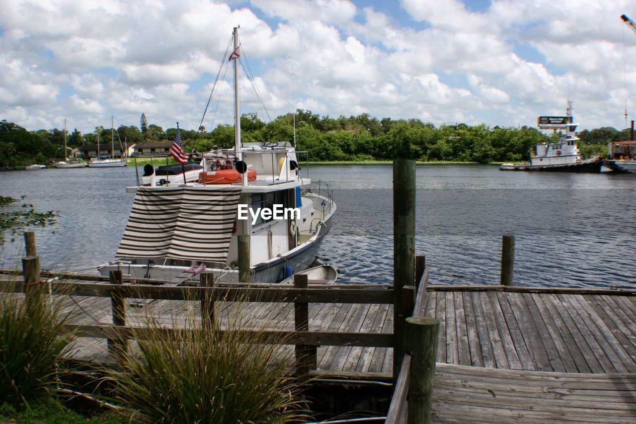 Boat moored on lake against cloudy sky