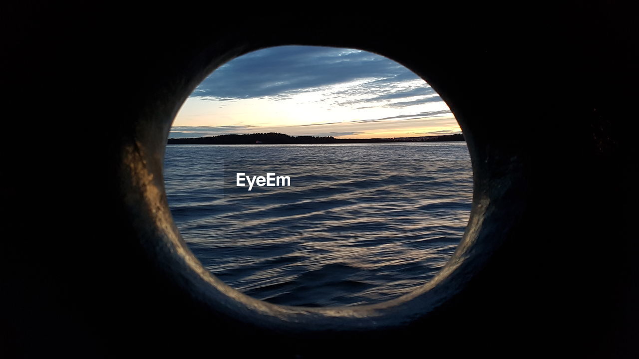 SCENIC VIEW OF SEA SEEN THROUGH WINDOW AT SUNSET