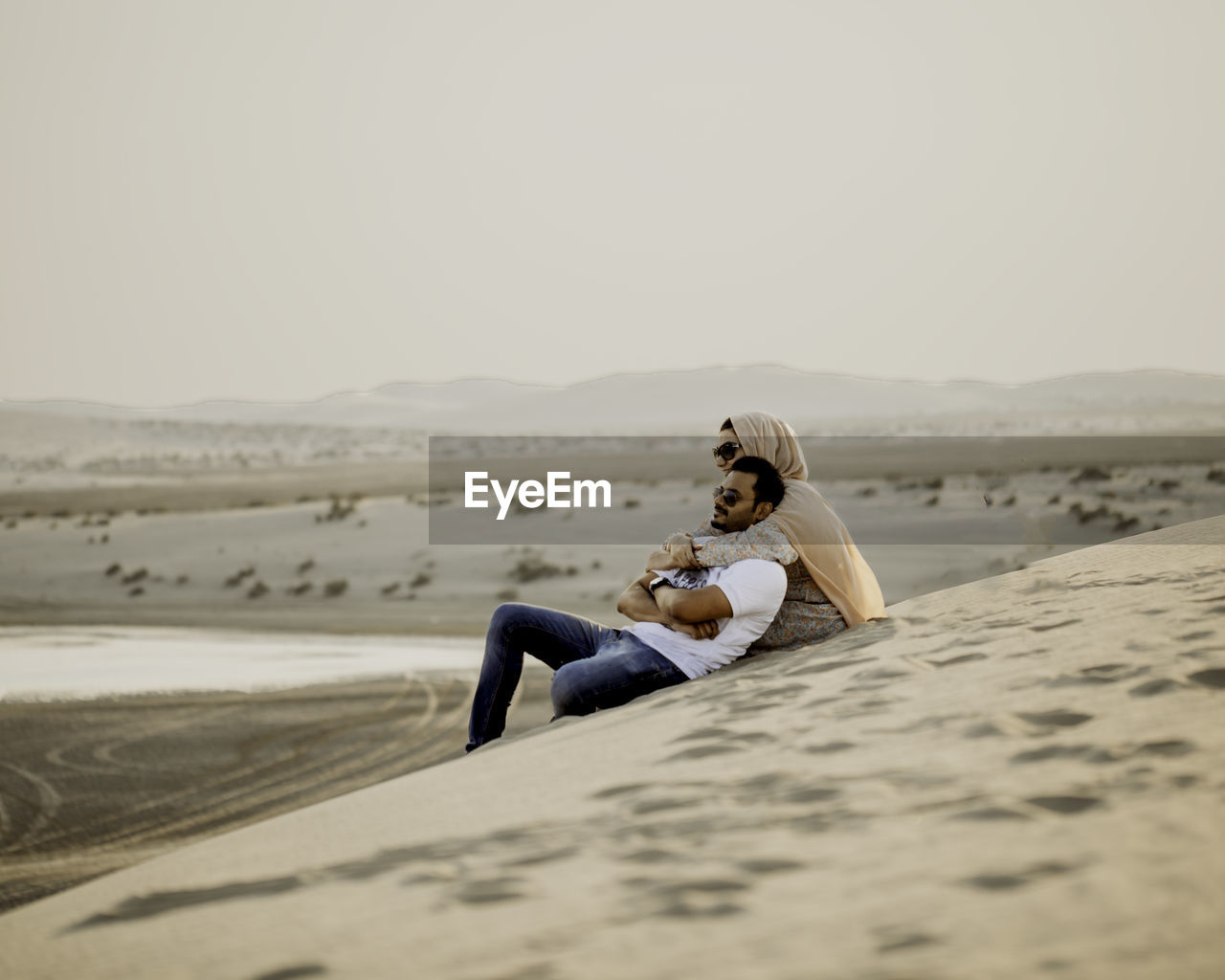 Couple sitting on sand in desert