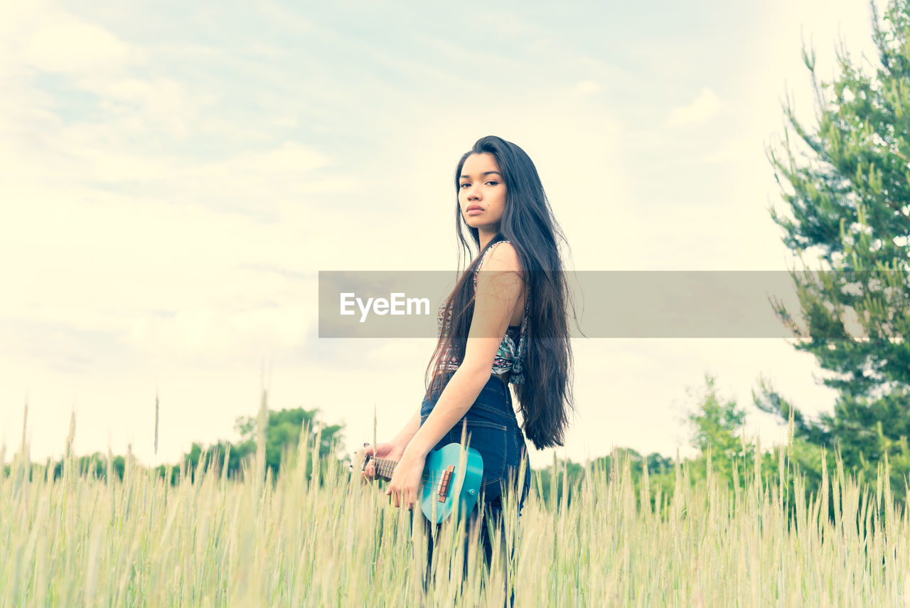 Young woman on field against sky