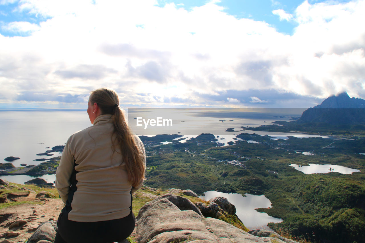 Rear view of woman standing on mountain against sky