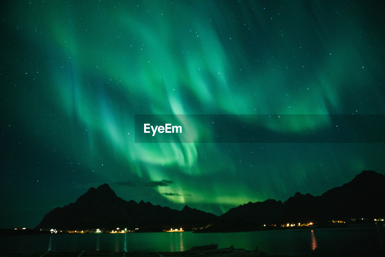 Scenic view of lake against green sky at night