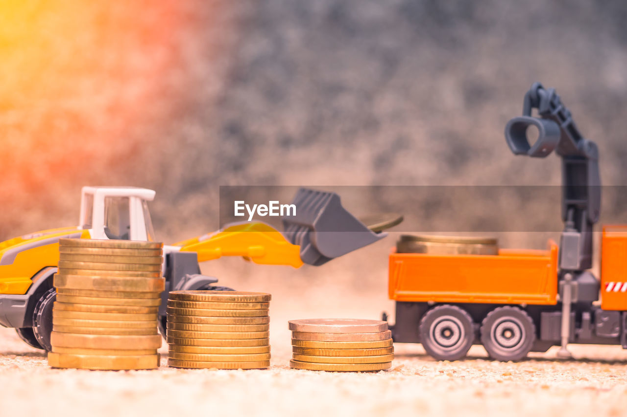 Close-up of coins stacked against toy bulldozers