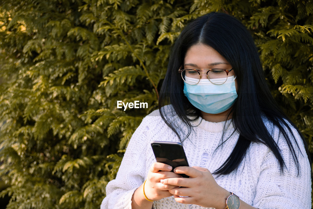 PORTRAIT OF YOUNG WOMAN USING MOBILE PHONE IN CAMERA AT SMART