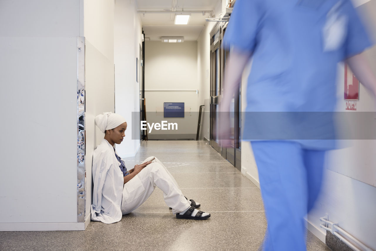 Female doctor sitting on hospital corridor floor