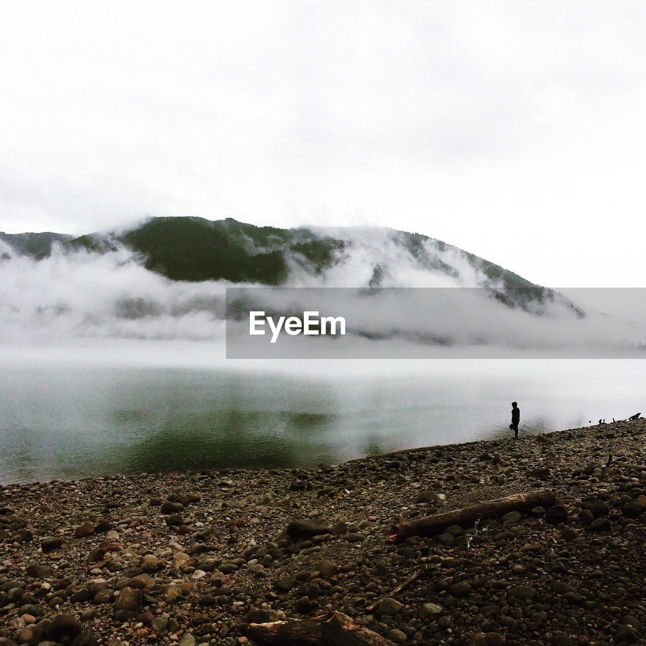 Silhouette person standing by yale lake against mountains during foggy weather