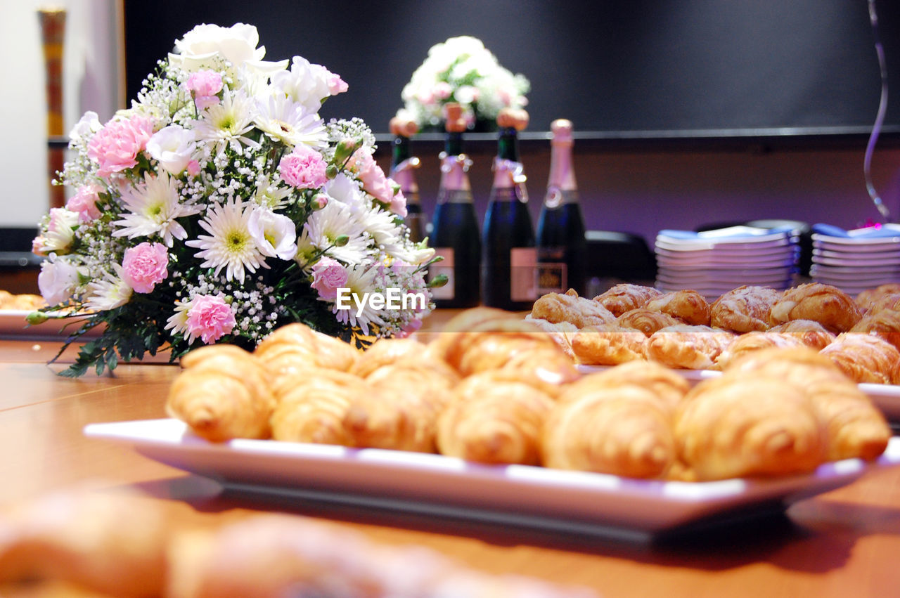 Close-up of croissants in plate with bouquet on table