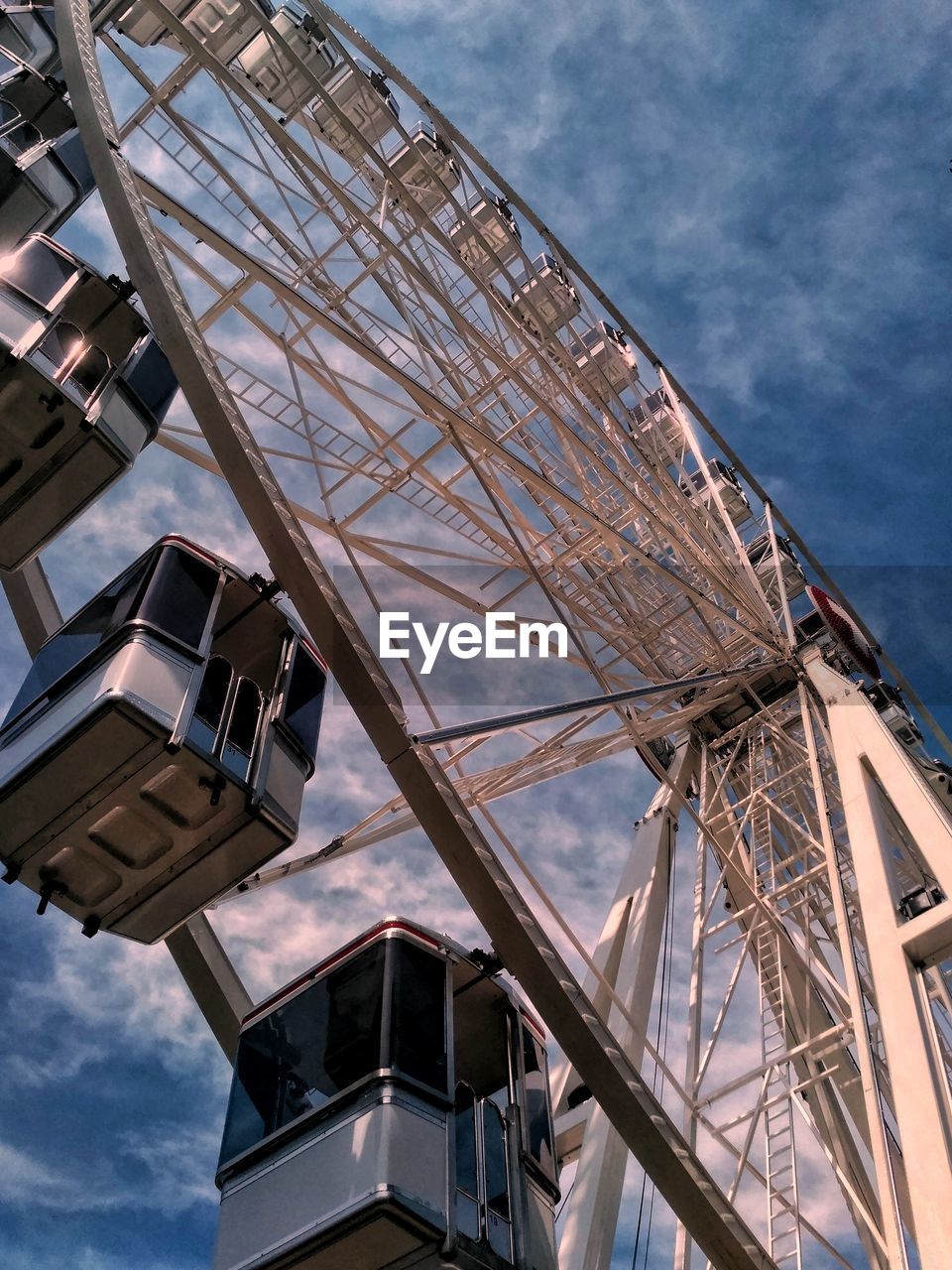 Low angle view of ferris wheel against cloudy sky