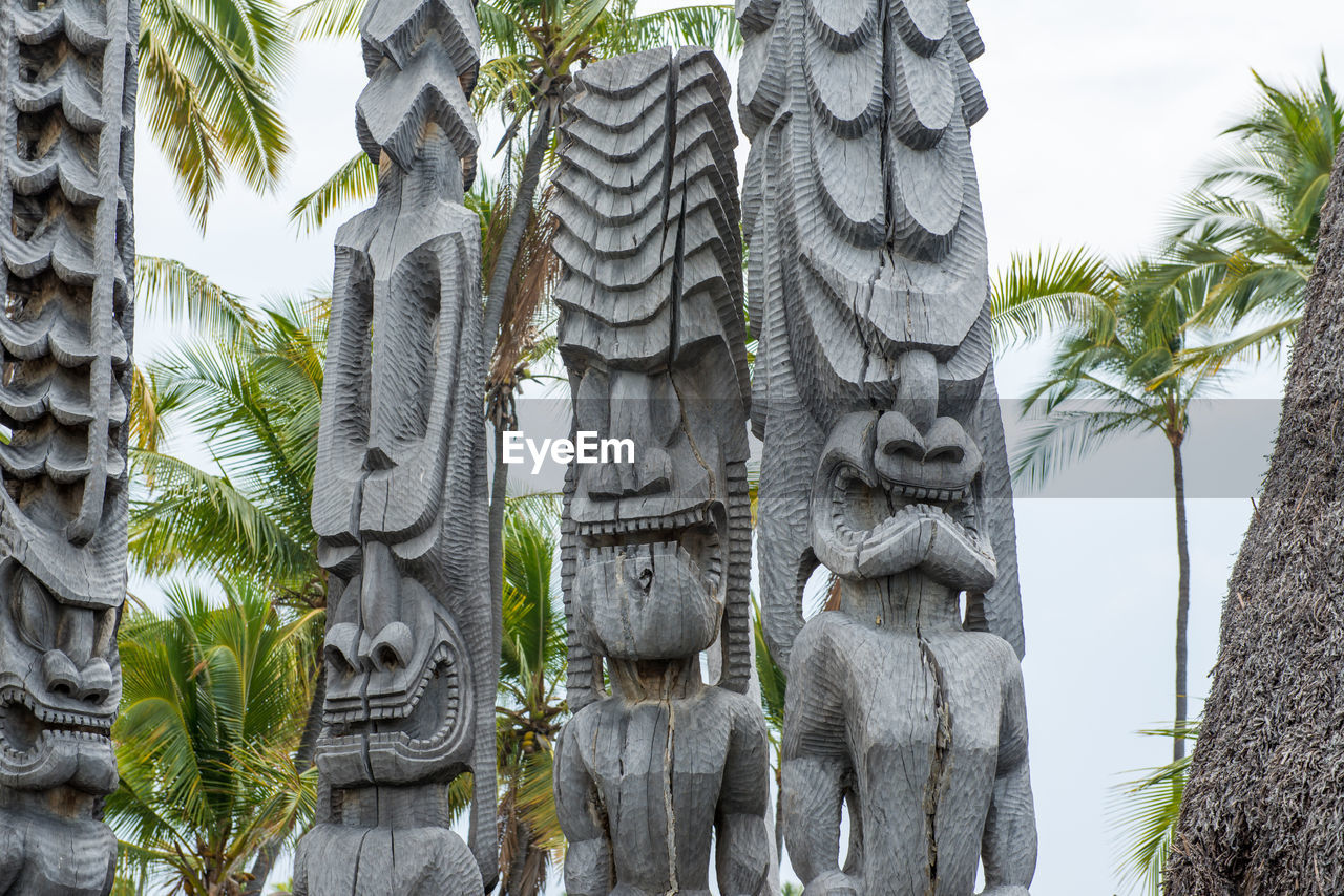 Low angle view of sculptures against trees and sky