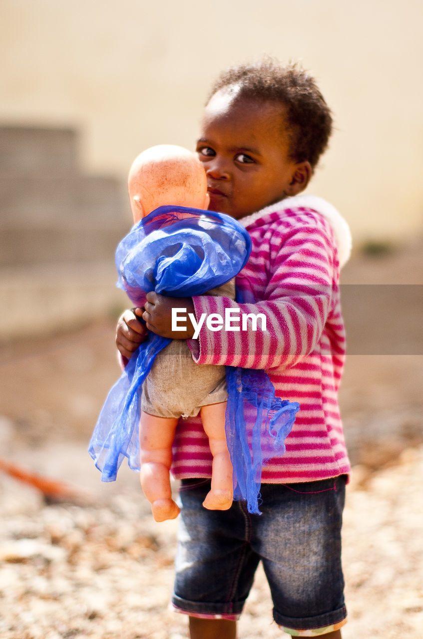 Portrait of boy with doll on footpath