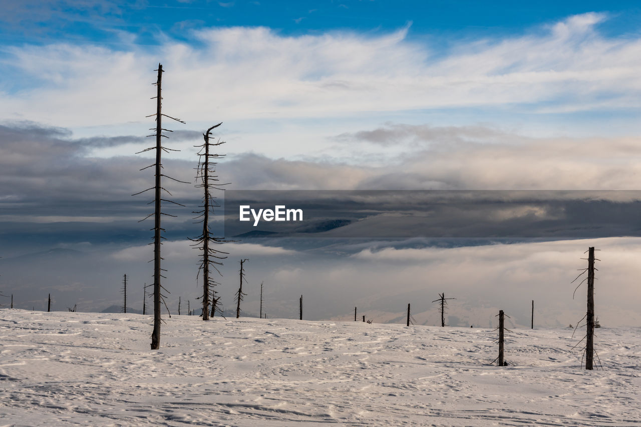 ELECTRICITY PYLON ON SNOWY LAND AGAINST SKY