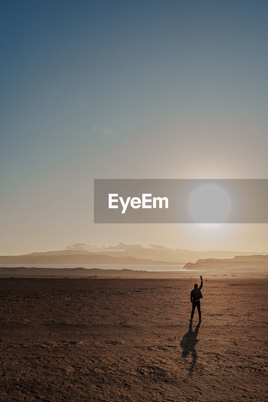 silhouette woman walking on beach against sky during sunset