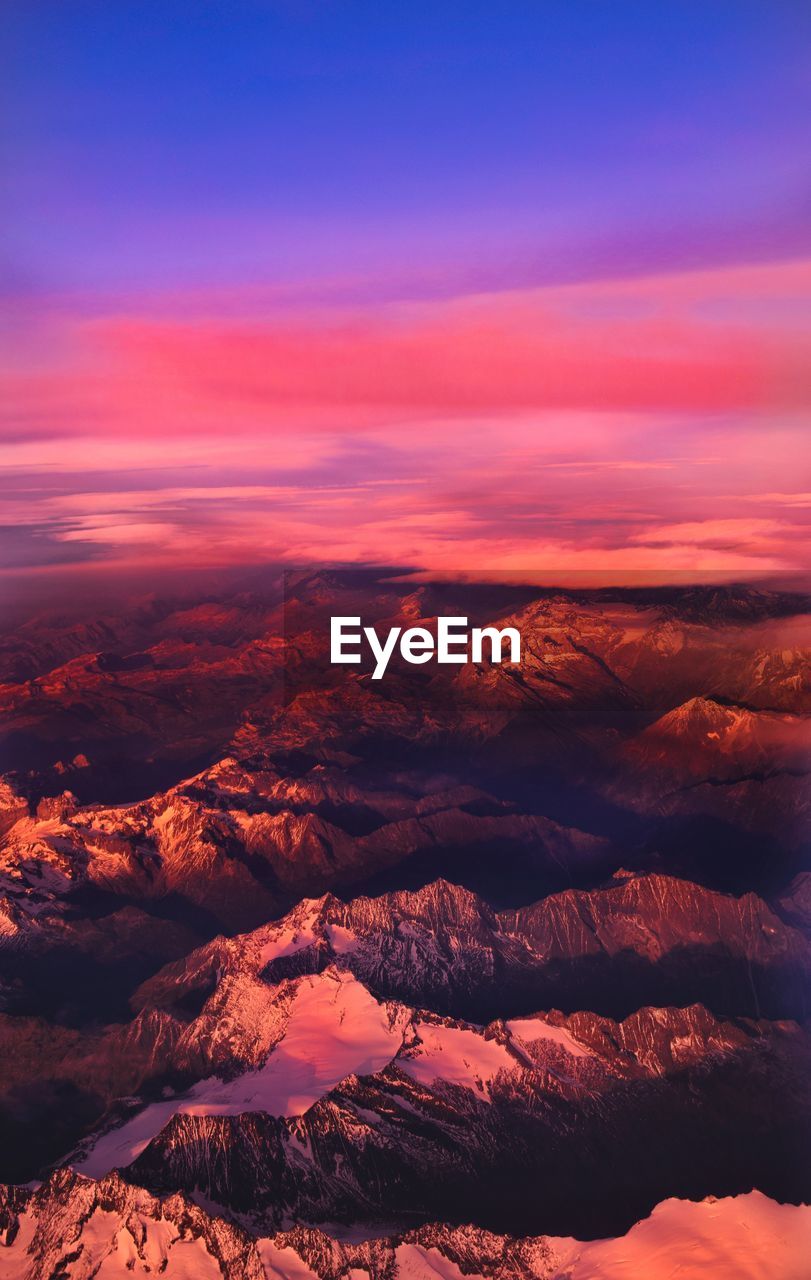 Aerial view of snowcapped mountains against sky during sunset