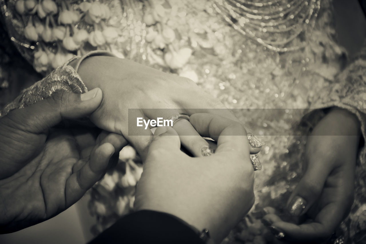 Cropped hands of man putting ring on finger