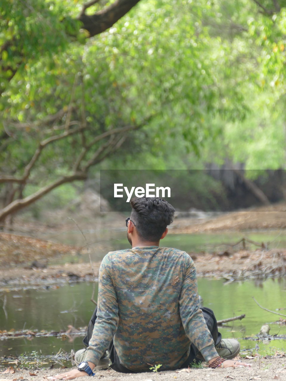 Rear view of man sitting on rock