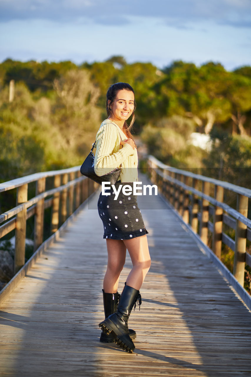 WOMAN STANDING ON FOOTBRIDGE AGAINST BRIDGE