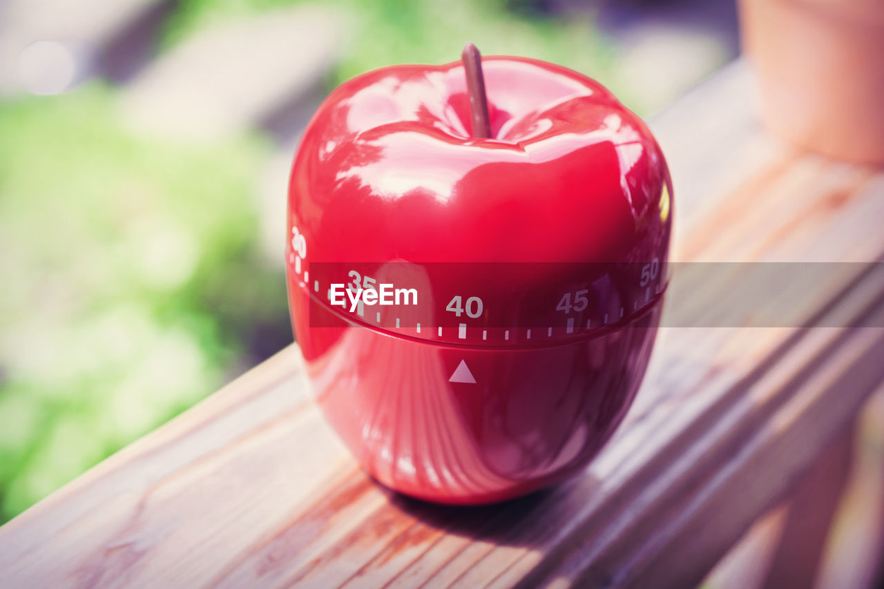 Close-up of red artificial apple on wooden railing