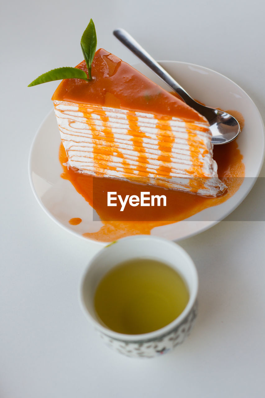 High angle view of cake in plate by thai tea on white background