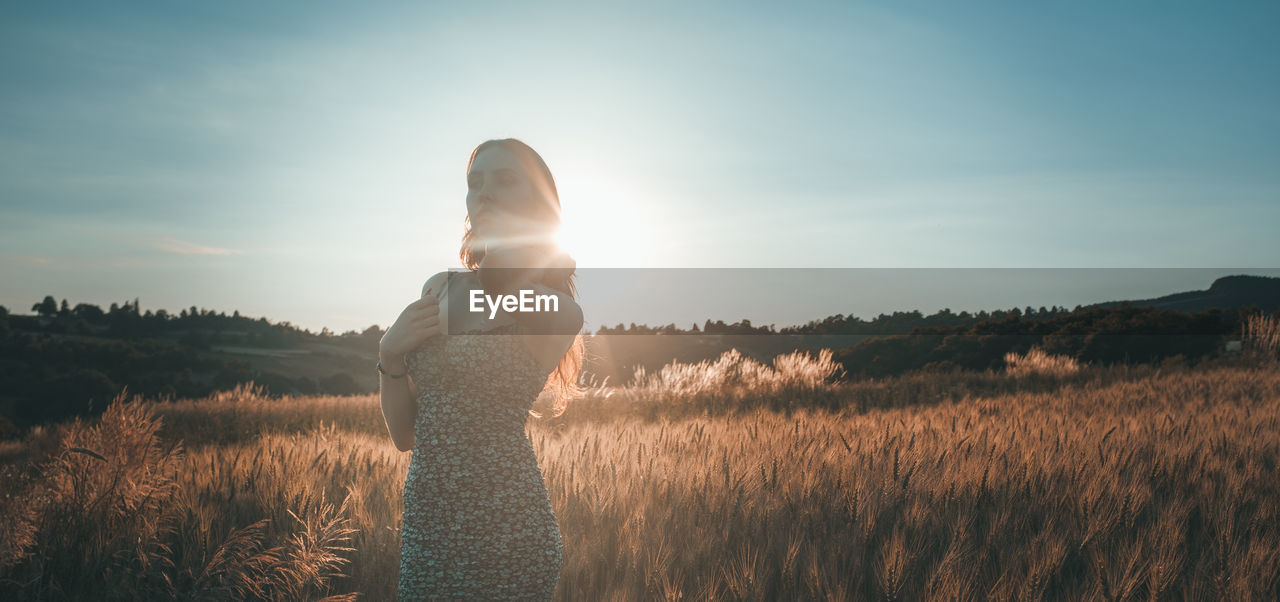 Woman standing on field against sky