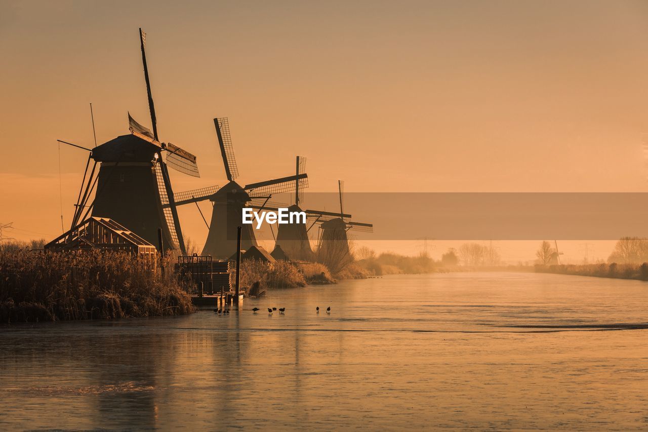 Traditional windmills by river during sunset