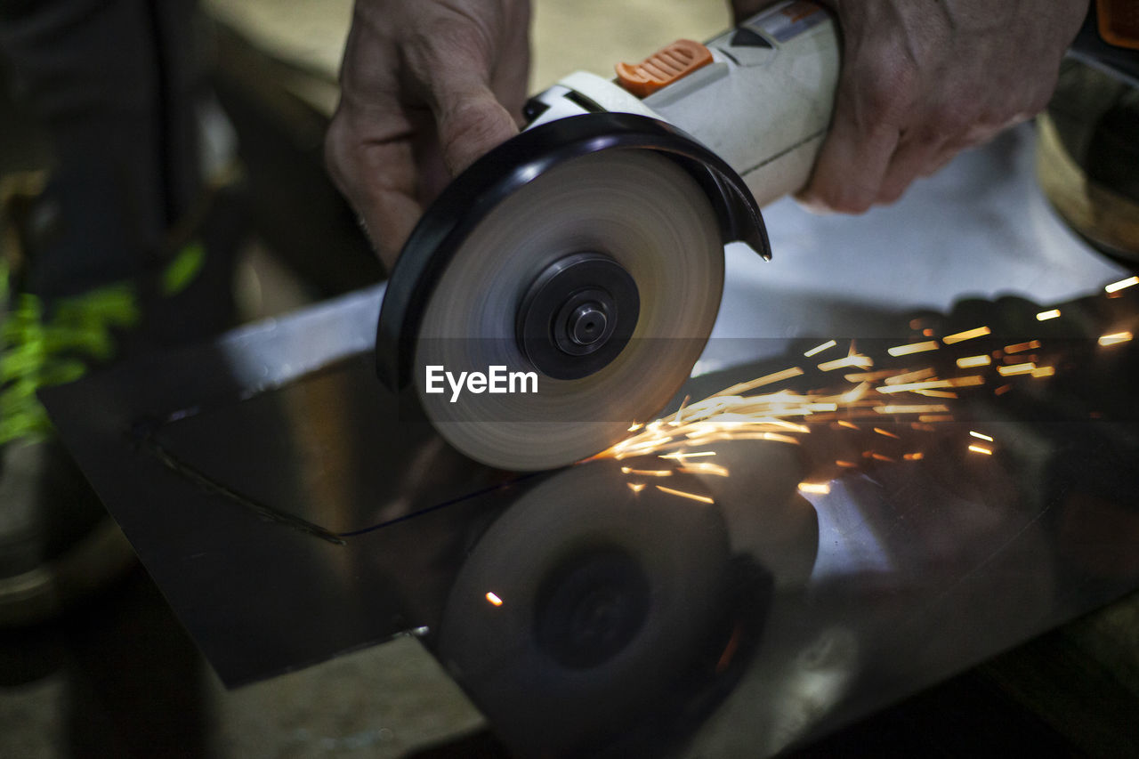 Cropped hand of manual worker grinding metal at workshop