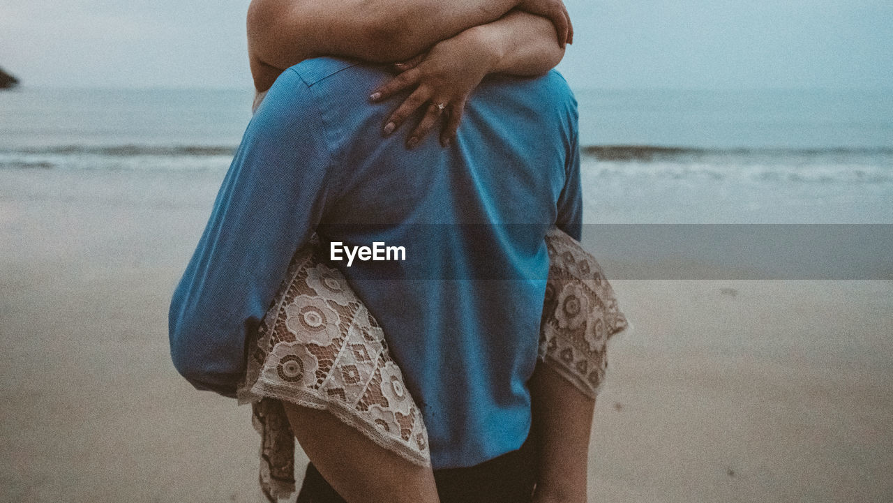 Midsection of romantic couple embracing at beach