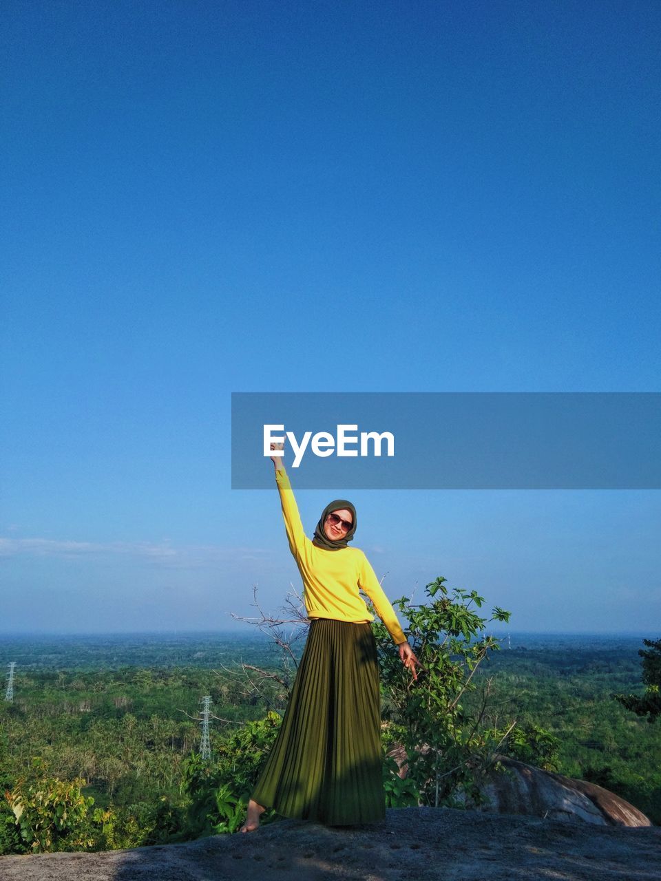 Young woman standing against blue sky