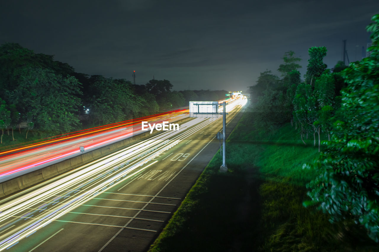 Light trails on road against sky at night