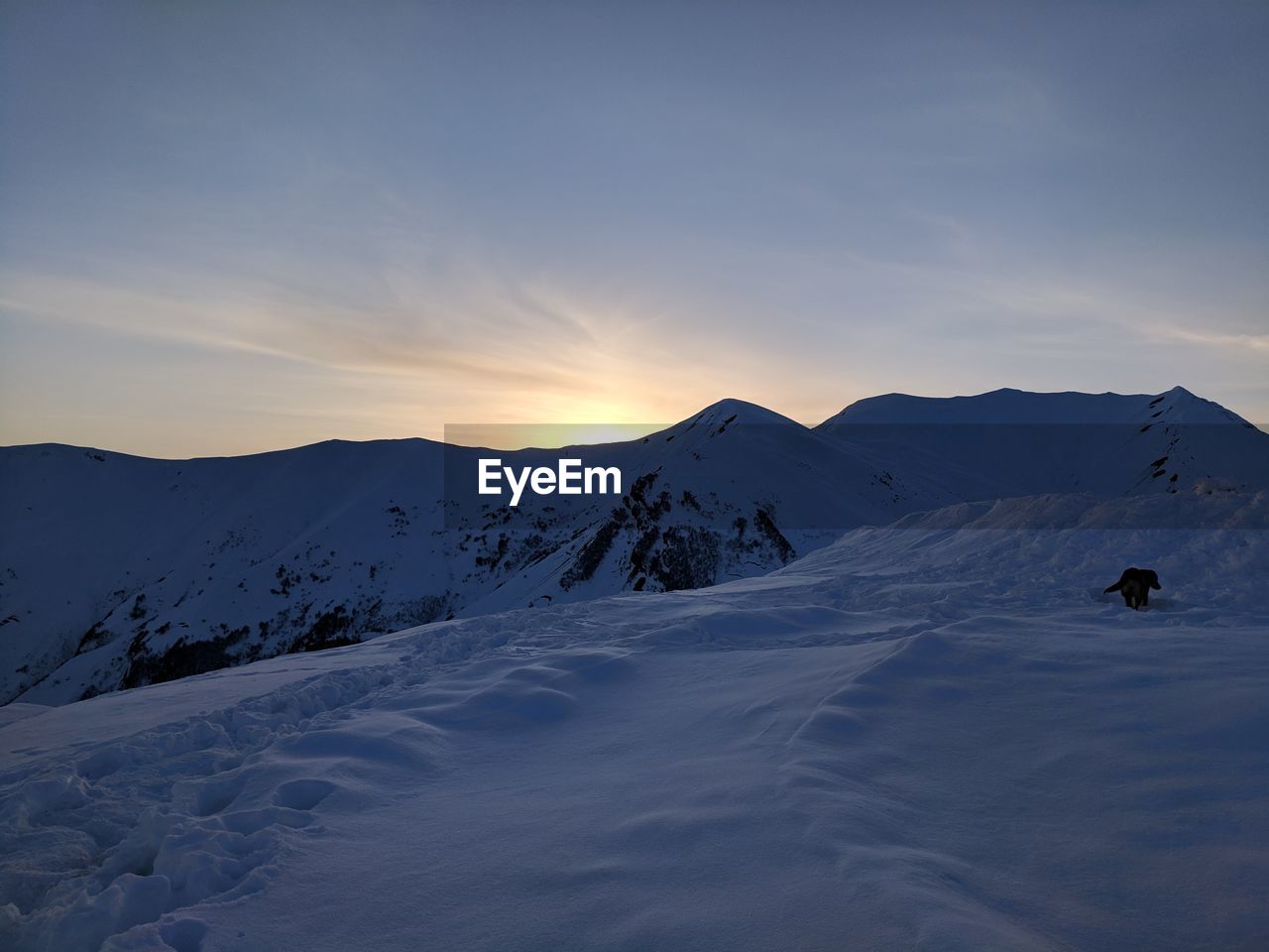 Scenic view of snow covered mountains against sky during sunset