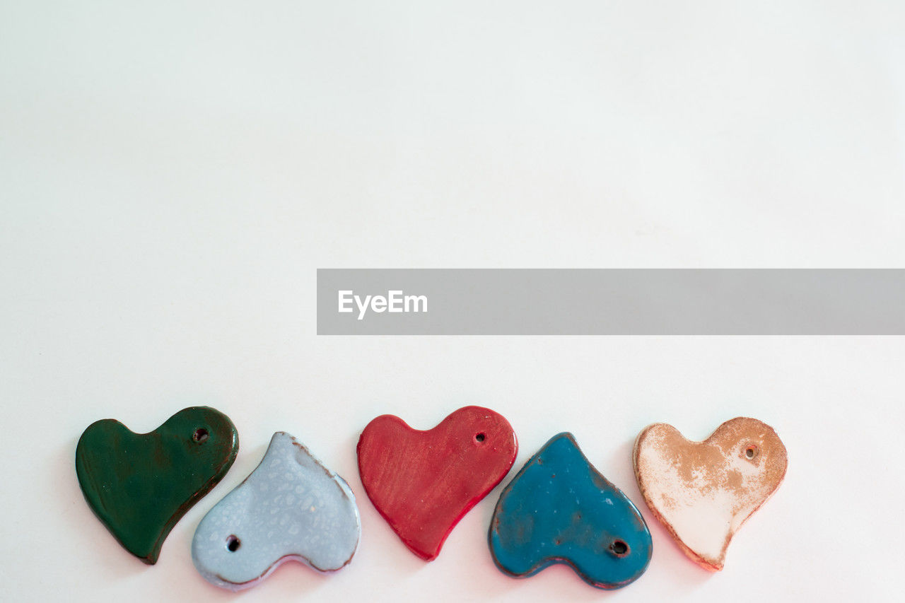 Diversity and love. small ceramic heart shaped pieces. white background