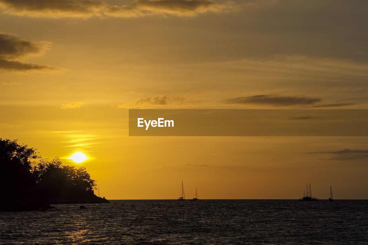 Silhouette of island and yacht boats on the horizontal line with light of sunset background