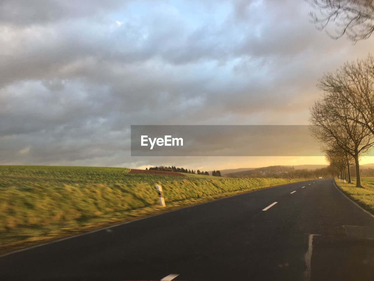 Road amidst agricultural field against sky