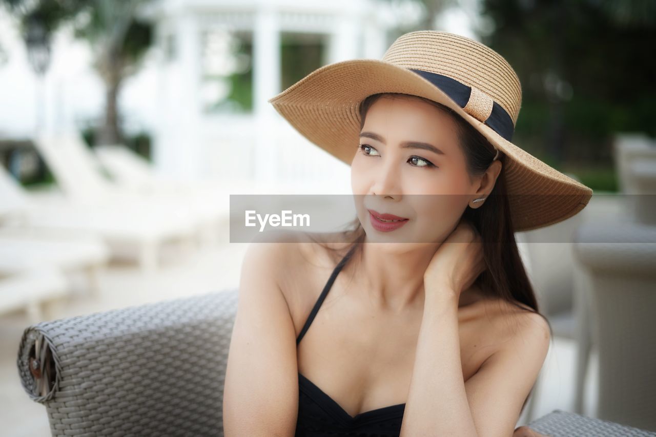 Beautiful young woman looking away while wearing hat