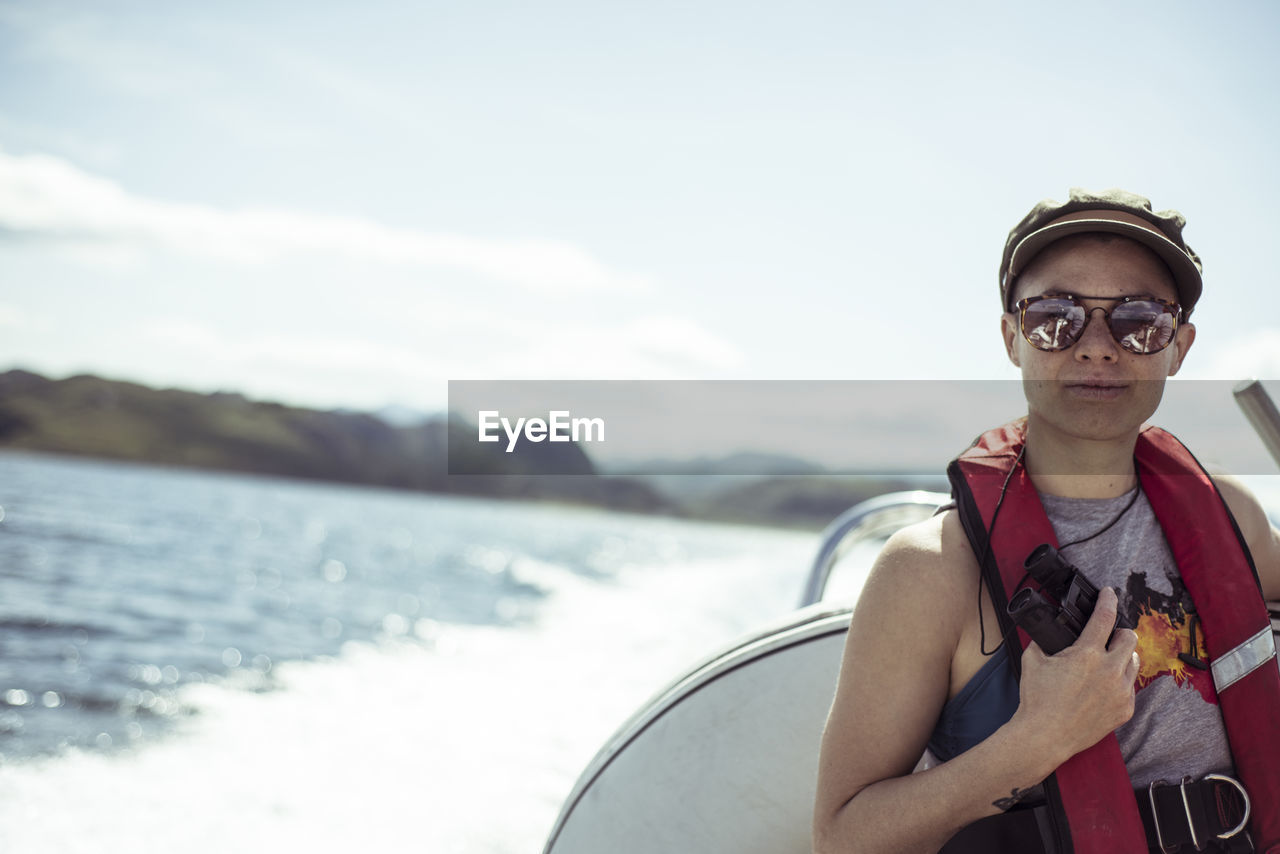 Girl on speed boat smiles in sunglasses and life vest