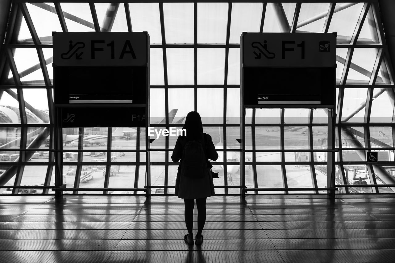 FULL LENGTH REAR VIEW OF WOMAN WALKING ON AIRPORT