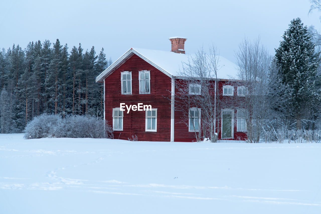 HOUSE ON SNOW COVERED FIELD AGAINST SKY