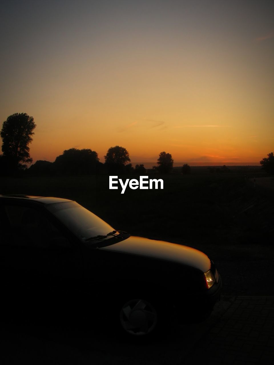 SILHOUETTE CAR ON ROAD AGAINST ORANGE SKY