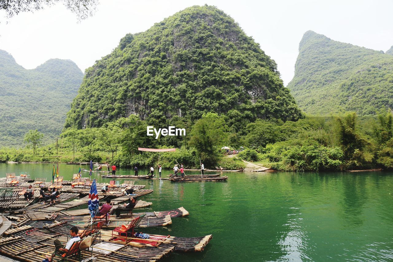 Bamboo rafts in river by mountain