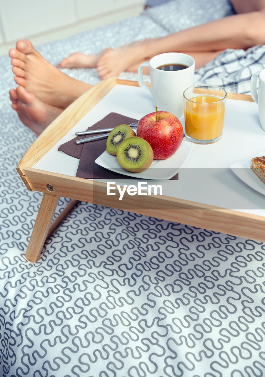 Low section of couple relaxing by table with food