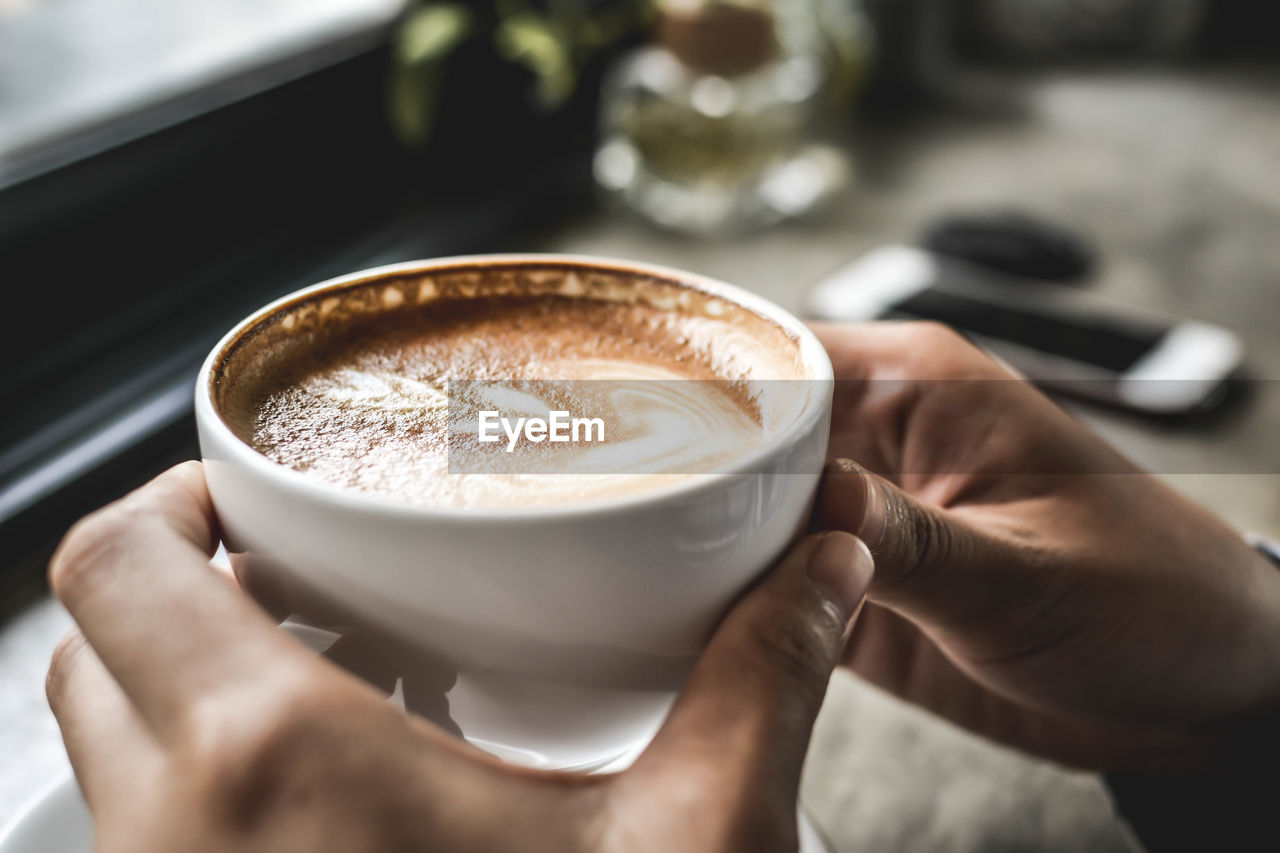 Close-up of hand holding coffee cup