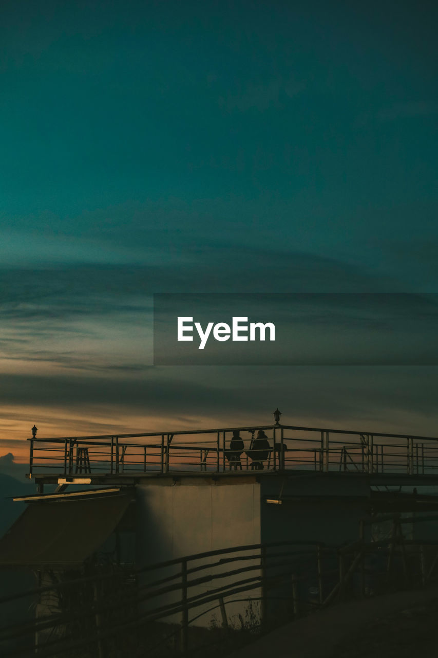 Silhouette pier over sea against sky during sunset