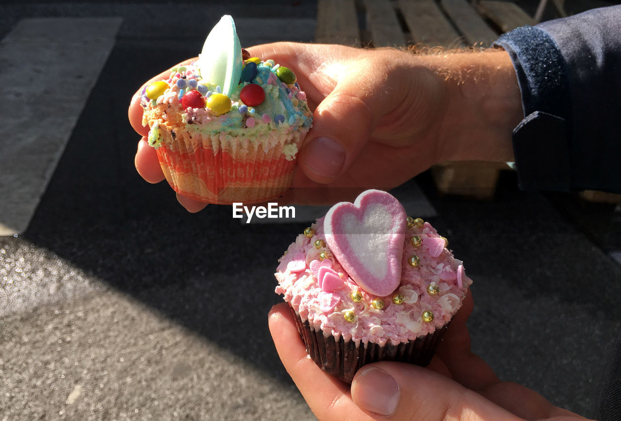 Cropped hand holding cupcakes