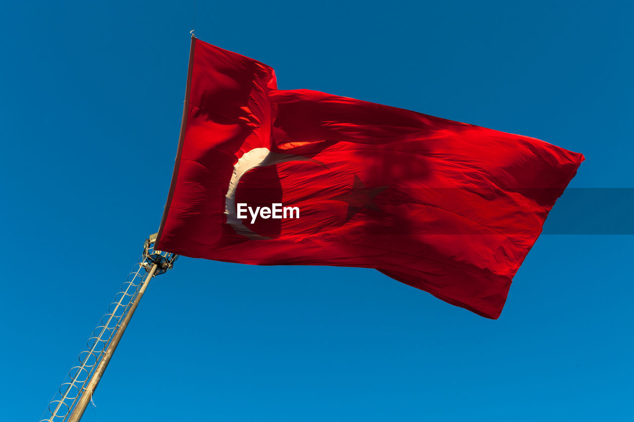 Low angle view of turkish flag against clear blue sky